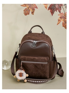 Close-up of quilted front pocket and plush charm on dark brown velvet backpack