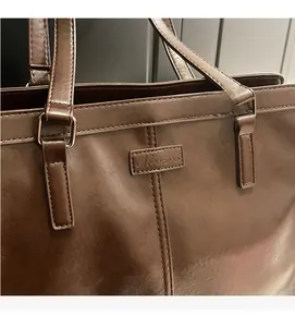 Close-up of the dark brown leather tote bag showing high-quality stitching and embossed logo
