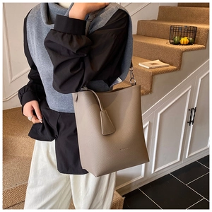 Detail of light brown lychee grain leather bucket bag with embossed logo on the side