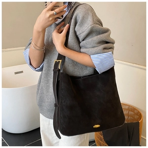 Detailed view of matte black shoulder bag featuring gold hardware and wide adjustable strap