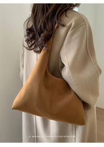Minimalist hobo bag in brown leather styled with a camel wool coat in a retro setting