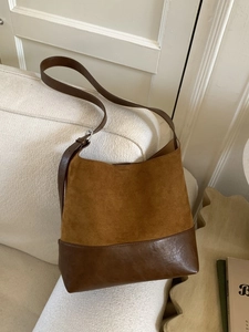 Retro brown bucket bag in suede and smooth leather on a white textured sofa
