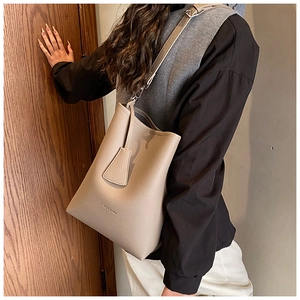 Close-up of beige pebble grain bucket bag with adjustable strap and HODOMU branding