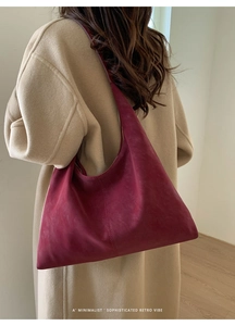 Detailed side view of a minimalist burgundy suede hobo bag on model's shoulder