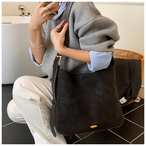 Close-up of the black matte suede tote bag featuring a golden square buckle detail
