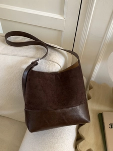 Vintage dark brown bucket bag in mixed leather finish shown on a soft cream sofa