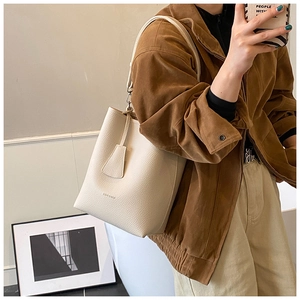 Detail of cream white bucket bag in lychee texture leather with branded embossed logo