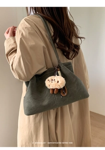Detail of a dark green faux suede tote bag with a cute plush sheep pendant accessory