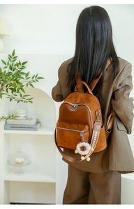 Detail of brown patchwork backpack with quilted pattern and plush sheep charm on a model