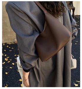 Detail of dark brown leather tote bag showing grainy texture and autumn street style