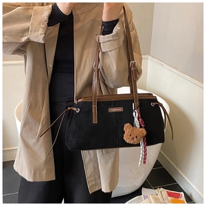 Detail of vintage suede tote bag showing fashion letter patch and brown plush bear charm