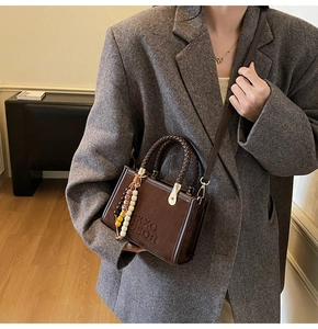 Detail of vintage brown suede handbag featuring embossed lettering and woven handles