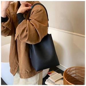 Detail of black lychee grain leather bucket bag featuring debossed HODOMU logo on surface