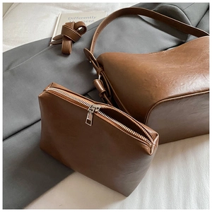 Close-up of the brown faux leather semi-moon tote bag and matching zipper clutch set
