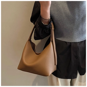 Close-up of brown litchi grain leather tote bag showing rich texture and adjustable strap