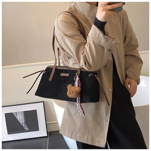 Detail of vintage black suede hobo bag with slim leather straps and plush bear charm