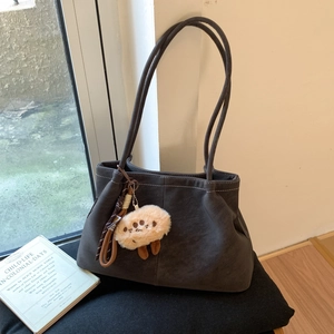 Detail view of coffee brown suede tote bag with contrast stitching and plush charm