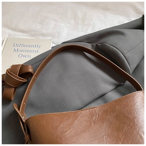Detail of caramel faux leather shoulder bag with fine texture and adjustable strap