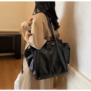 Detail of a black large-capacity tote bag with glossy texture and decorative stitching
