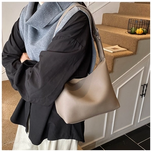 Close-up of khaki pebbled leather shoulder bag shown on a model in a minimal setting