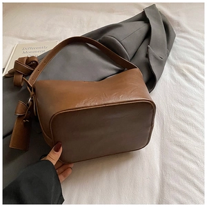 Macro detail of brown retro leather bucket bag showing wide base and texture
