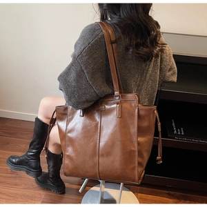 Close-up of brown tote bag featuring side drawstrings and premium leather texture