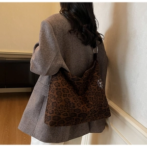 Detail view of large leopard print crossbody bag featuring crescent shape and silver zippers