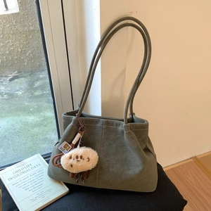 Detail view of green suede tote bag with white stitching and plush sheep charm