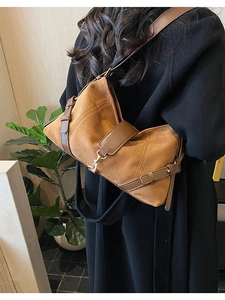 Sac sous le bras en daim marron avec sangle décorative porté à l'épaule dans un décor épuré