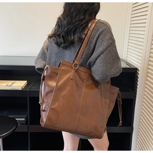 Detail of vintage brown leather tote bag showing side drawstring and metal buckle