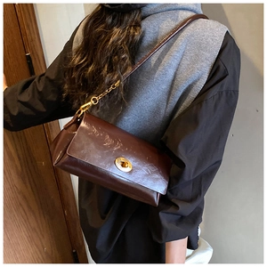 Detail view of dark brown retro leather shoulder bag with a gold round twist lock closure