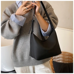 Detail of black pebbled leather texture and adjustable silver buckle on large hobo bag