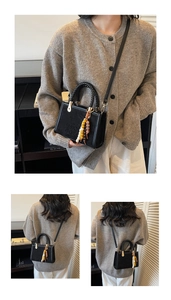 Close-up of black suede crossbody bag with woven handle and colorful beaded keychain