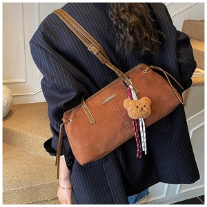 Detail of dark brown faux suede shoulder bag with a cute plush bear charm accessory