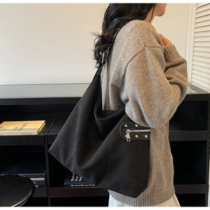Detail of black suede tote bag with silver studs and a functional side zipper pocket