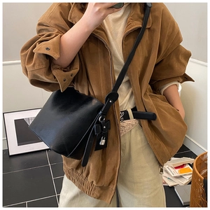 Mirror selfie showing the black matte leather bucket bag with a bow charm and long strap