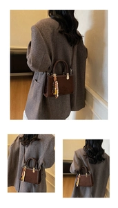 Close-up of brown suede handbag with woven handle and colorful beaded charm detail