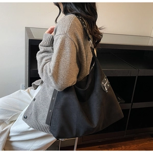 Side view of large black canvas shoulder bag with metallic eyelets and rivet details