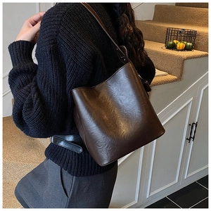 Detailed view of dark brown faux leather bucket bag with wide shoulder strap for women