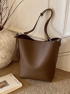 Deep brown pebble leather bucket bag with shoulder strap and minimalist design