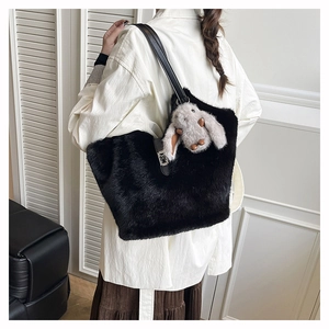 Detail of black faux fur tote bag with leather strap and cute rabbit plush charm