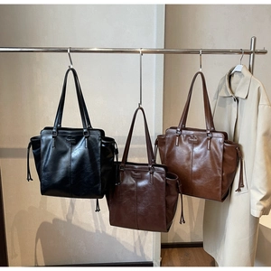 Close-up of three vintage tote bags in black, dark brown, and caramel leather