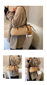 Detail of khaki suede underarm bag with bear charm and leather trim on a model