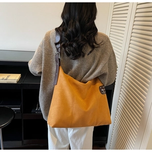 Detail view of large mustard yellow faux suede tote bag with brown adjustable strap