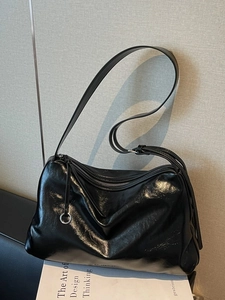 Minimalist black glossy leather tote bag with wide strap on white books
