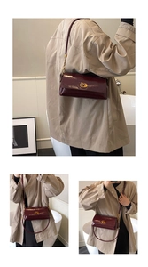 Detail of burgundy patent leather shoulder bag with vintage gold-tone twist lock and strap