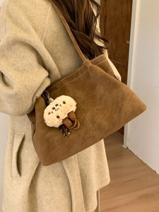 Large caramel suede tote bag with long shoulder straps and a cute plush charm on model