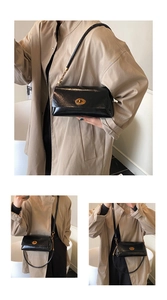 Close-up of black glossy shoulder bag with golden oval twist lock and adjustable strap