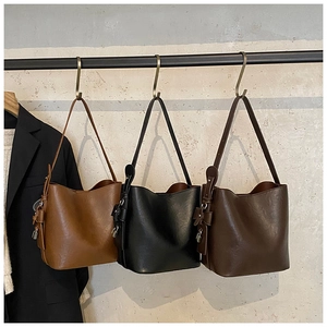 Three leather bucket bags in tan, black and brown hanging with padlock ornaments