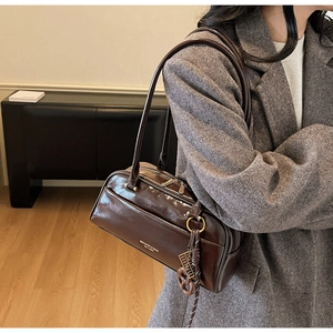 Detailed shot of brown faux leather shoulder bag with vintage metal charms and metal zipper